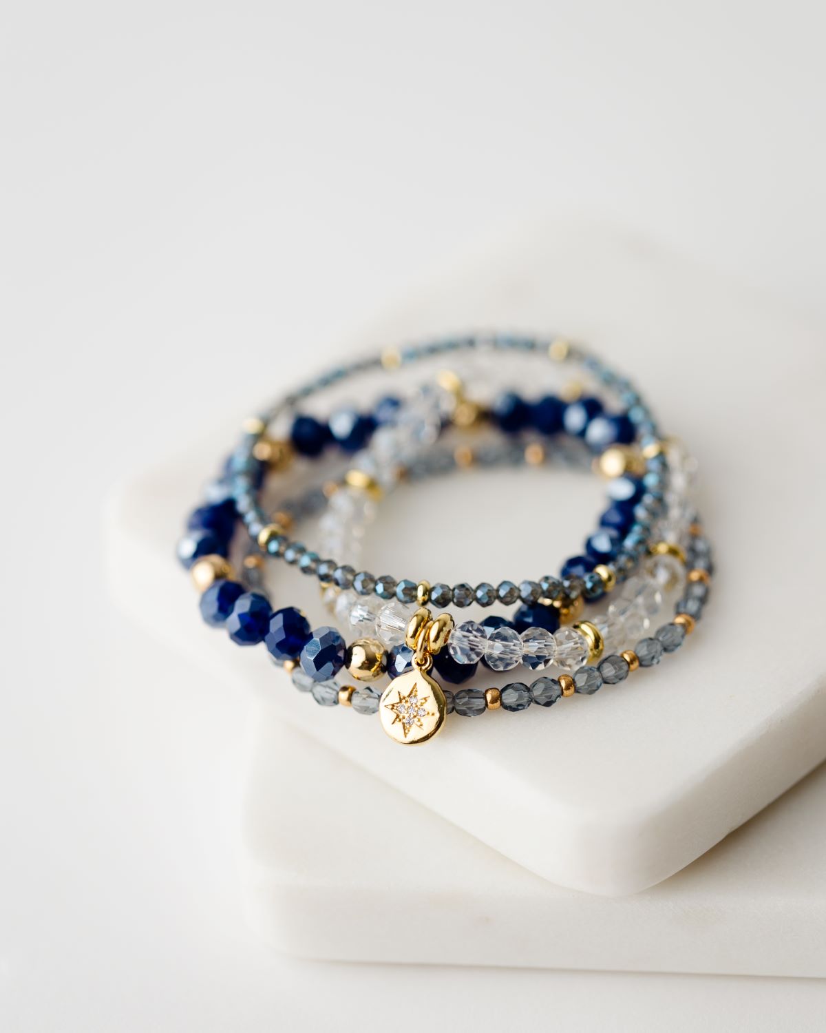 set of four blue and clear beaded bracelets with gold accents