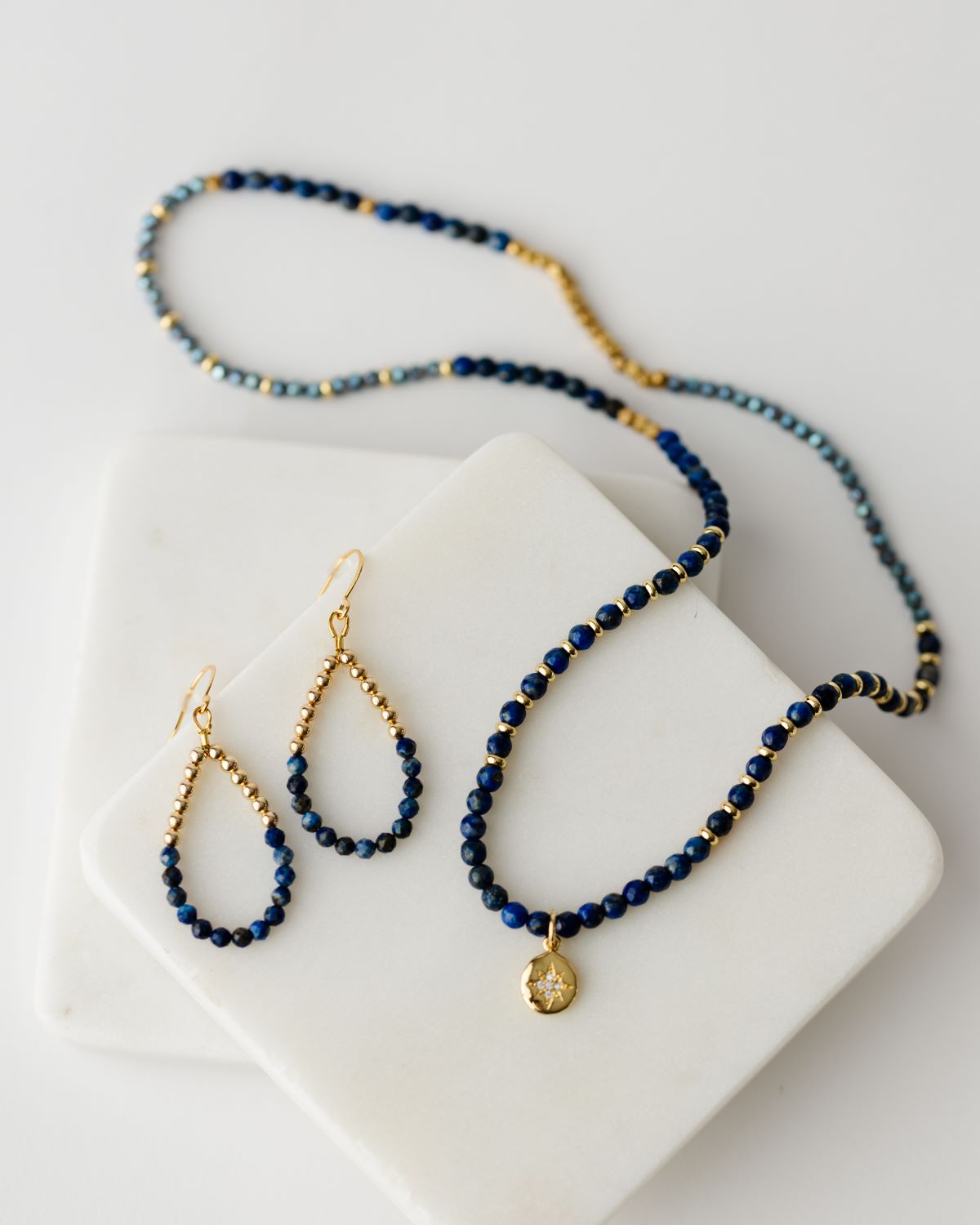 20" stretch cord to be worn as a necklace or wrap bracelet, featuring gold and blue beads and a gold north star pendant and gold bead and lapis teardrop earrings