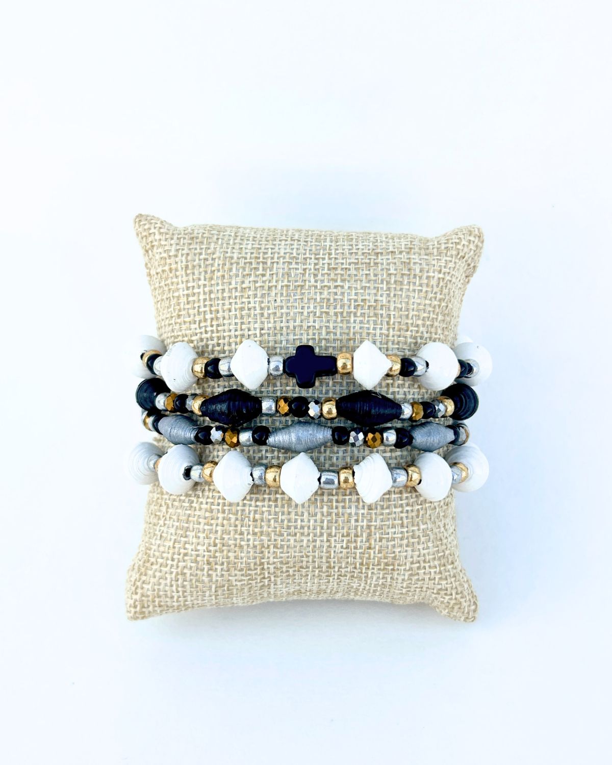 Set of beaded bracelets on a textured pillow with a white background