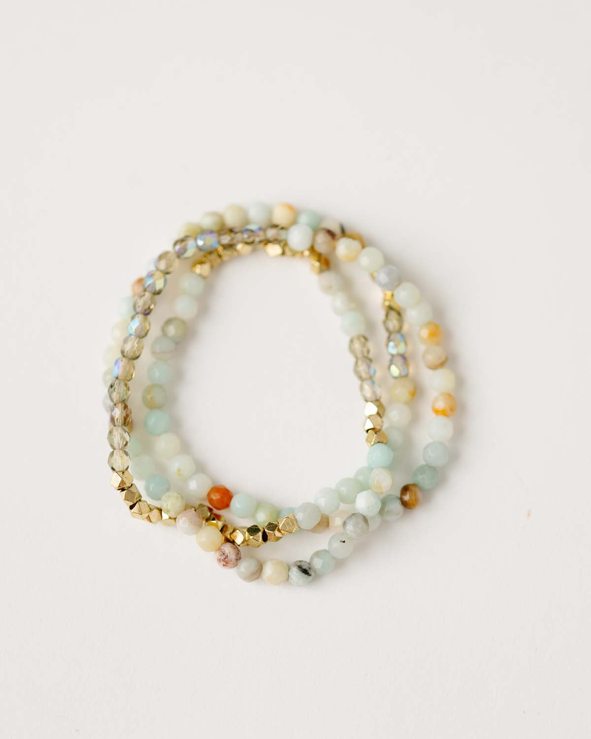 A beaded bracelet/necklace made with Amazonite stones, faceted glass, and gold-plated beads displayed on a white background.