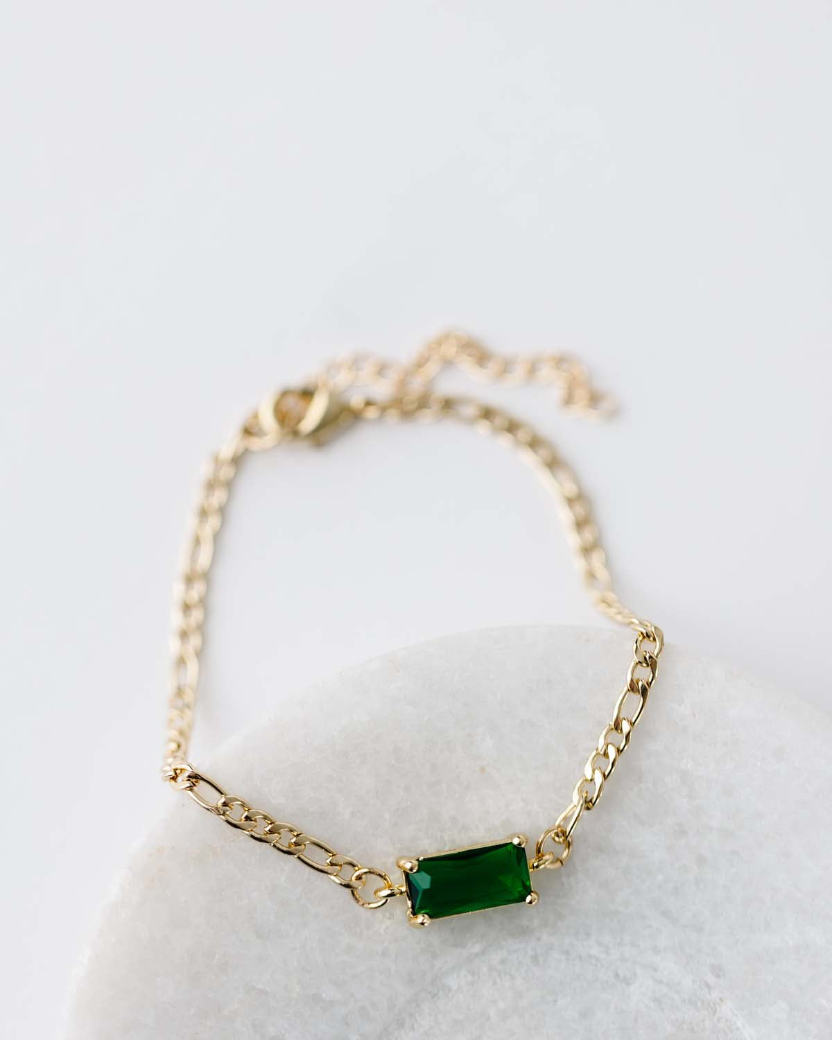 Gold figaro chain bracelet 6.5" with 2" extender. Rectangle emerald green CZ connector.