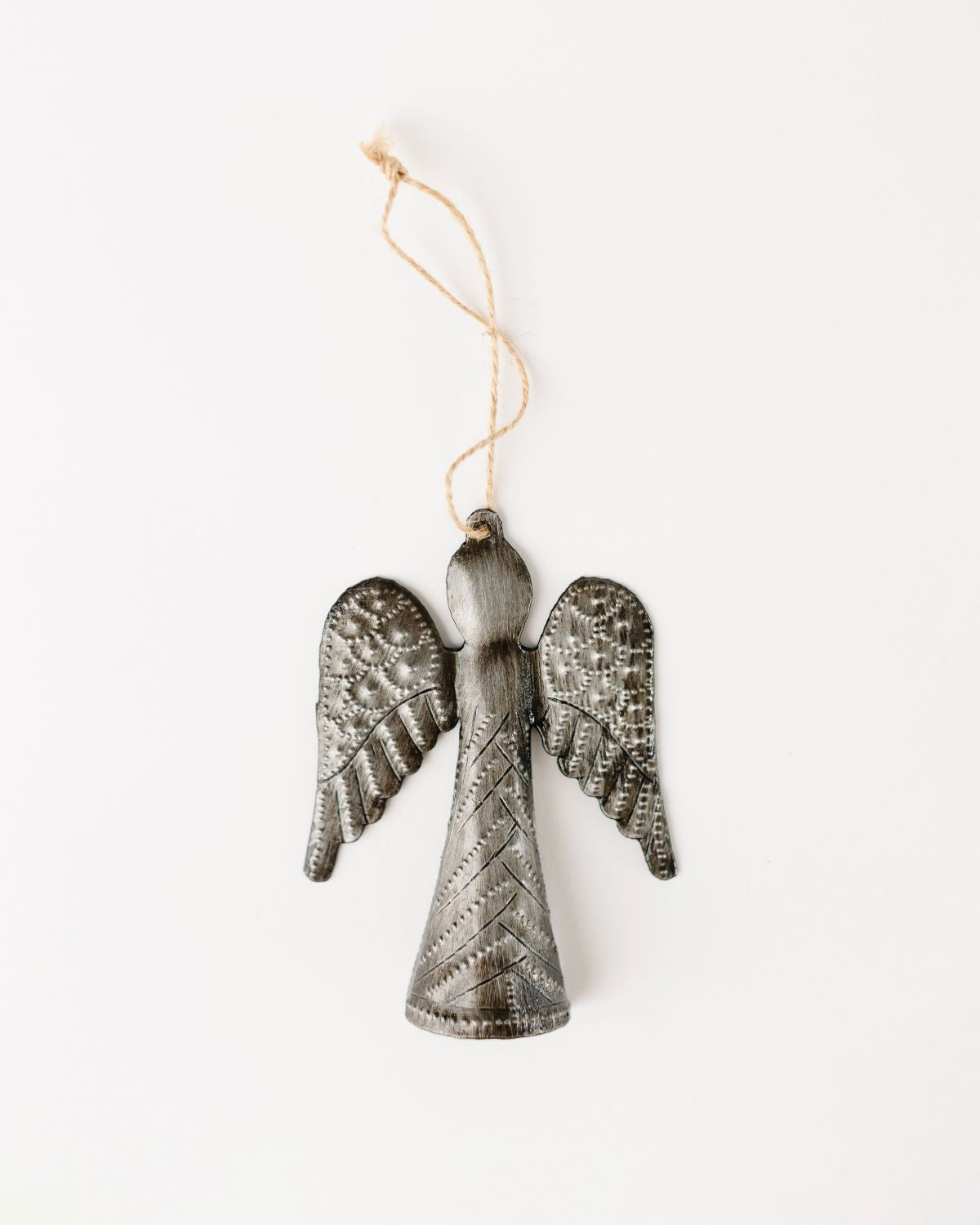 A handcrafted metal angel ornament made from recycled oil drums, with a textured pattern, hanging by a string.