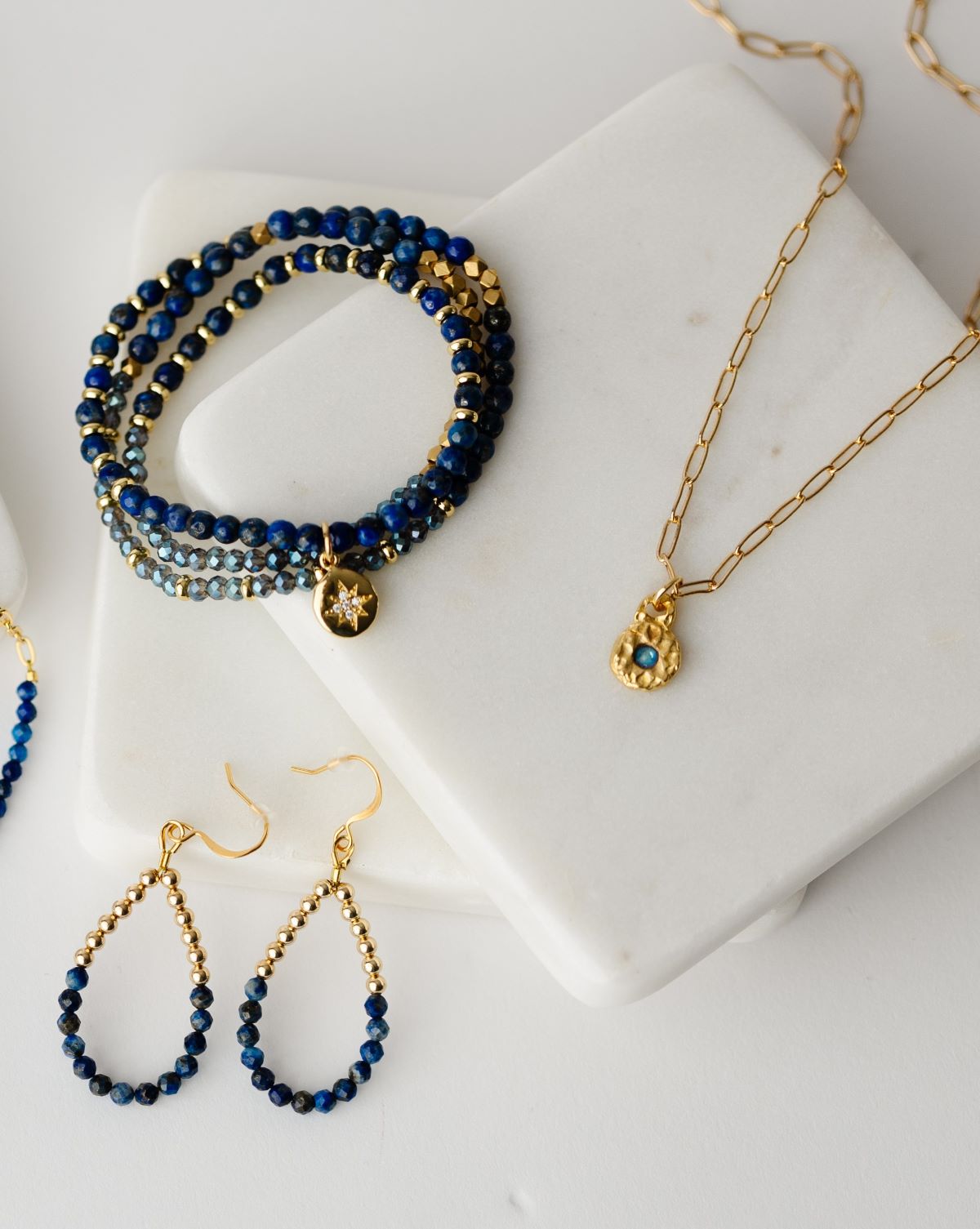 20" stretch cord to be worn as a necklace or wrap bracelet, featuring gold and blue beads and a gold north star pendant and gold bead and lapis teardrop earrings