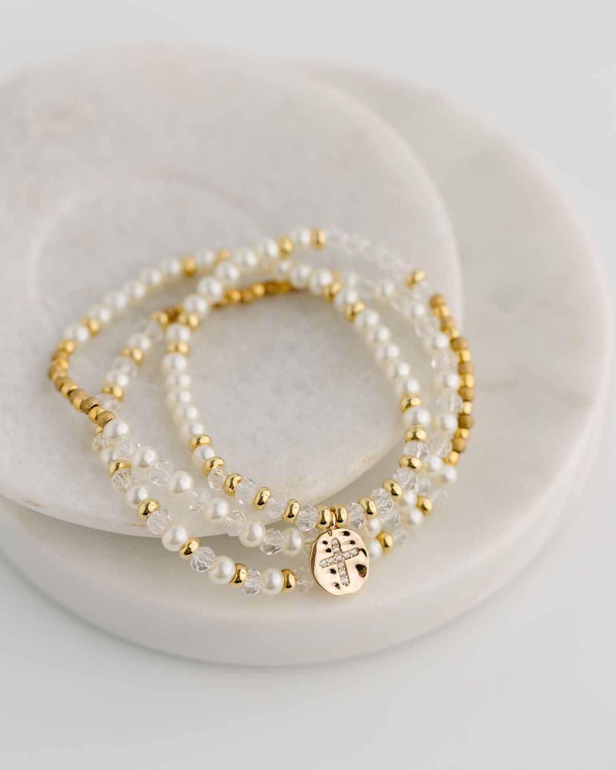 Set of pearl and gold beaded bracelets on a white plate