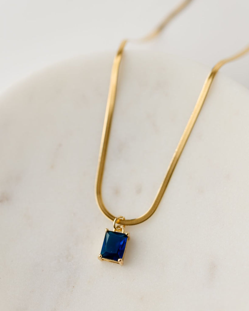 Dark blue cubic zirconia rectangular pendant in 24k gold setting on a 17.5" gold plated herringbone chain
