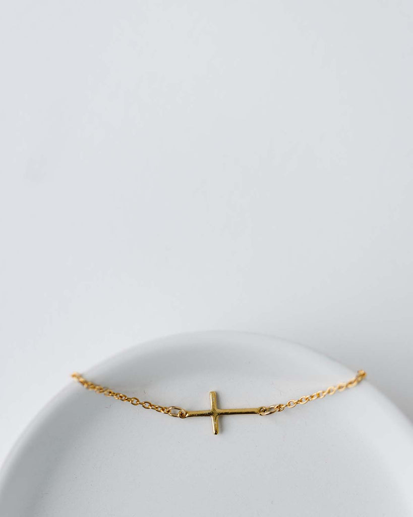 cross charm connector on a gold chain bracelet