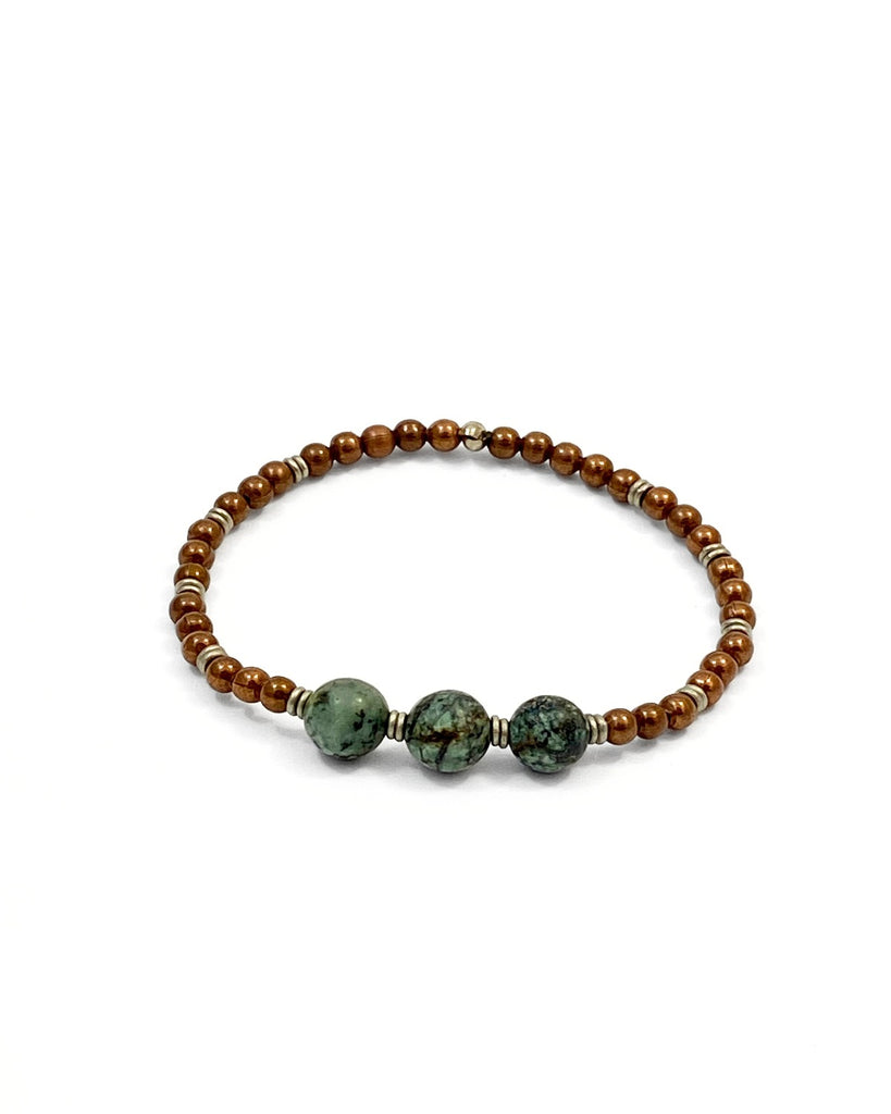 A stretch bracelet with copper beads and silver spacers with three African turquoise beads in the front.