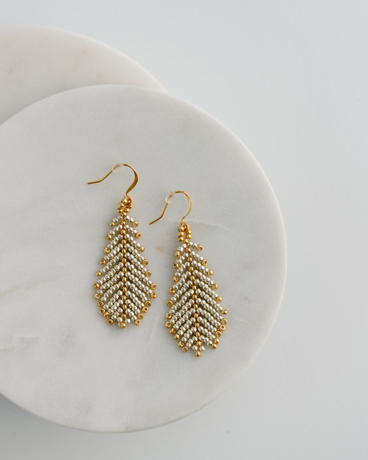 Gold beaded earrings on a white plate
