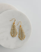 Gold beaded earrings on a white plate