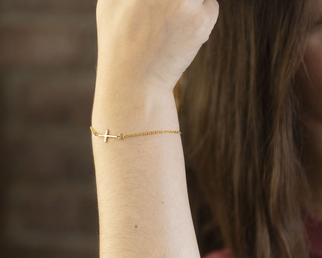 gold sideways cross bracelet on gold chain.
