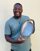 Man holding a decorative metal object against a plain background