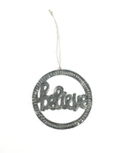 A metal art ornament with the word 'BELIEVE' inscribed in a circular pattern, with a hanging ribbon at the top.